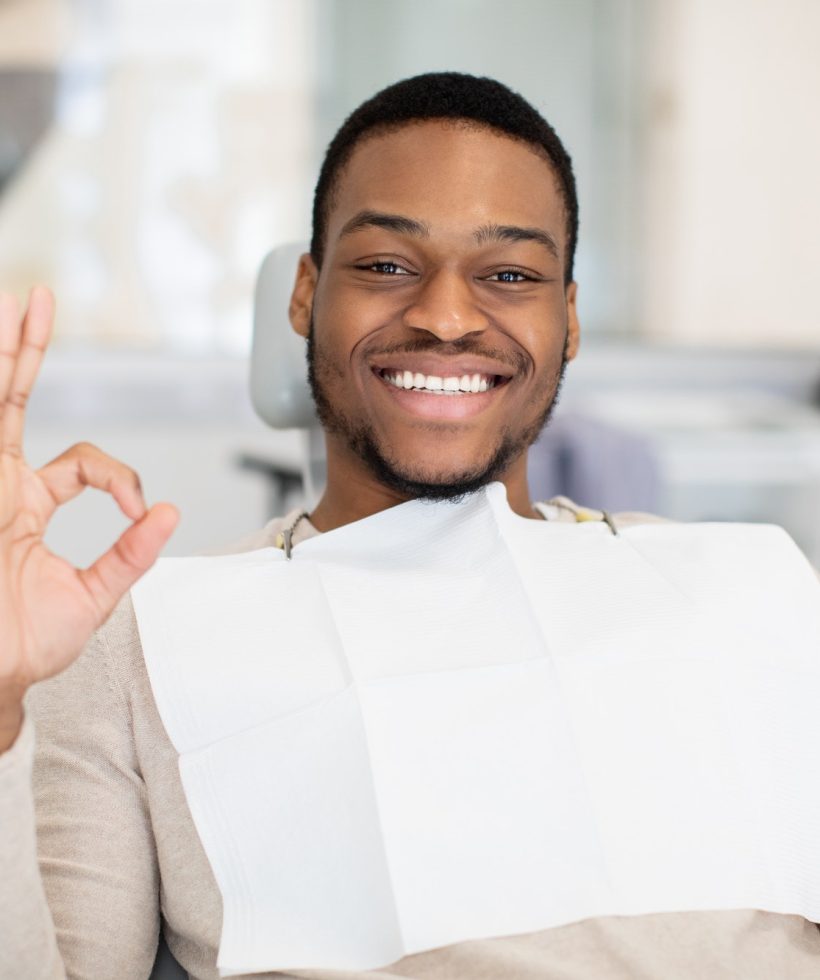 happy-black-male-patient-sitting-in-dentist-chair-and-showing-ok-sign.jpg